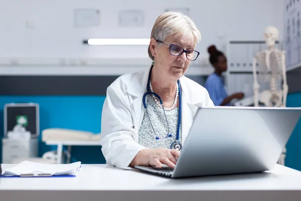 Retrato de médico com estetoscópio usando laptop para trabalhar em cuidados de saúde na clínica — Fotografia de Stock