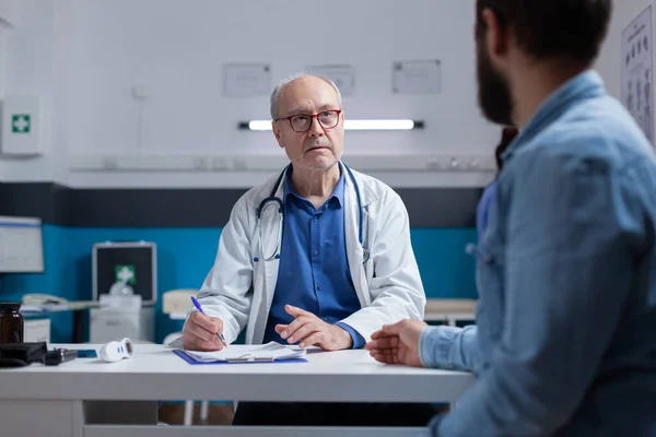 Arzt und Patient diskutieren bei Kontrollbesuch über Diagnose — Stockfoto