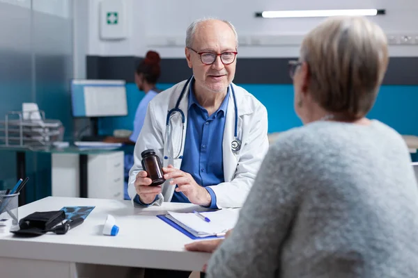 Arzt gibt alten Patienten bei Besprechungstermin im Kabinett Flasche Pillen mit Medikamenten — Stockfoto