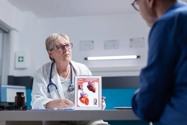 Facharzt spricht mit Mann über kardiologische Diagnose mit Bild des Herzorgans auf Tablet — Stockfoto