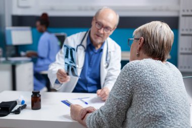 Teşhis ve tedaviyi bulmak için röntgen taraması sonuçlarını inceleyen doktor ve kadın.