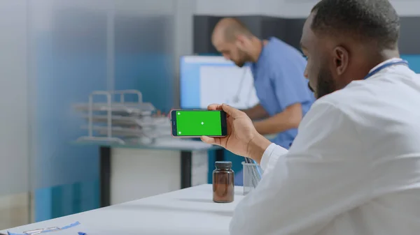 Médecin spécialiste afro-américain regardant se maquiller écran vert chroma smartphone clé — Photo