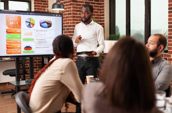 Hombre de negocios afroamericano explicando gráfico de gestión de pie frente a monitor — Foto de Stock