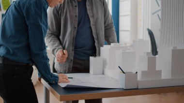 Kadın ve erkek bina modeli ve maketi tasarlamak için kağıt üzerinde planlar yapıyorlar.