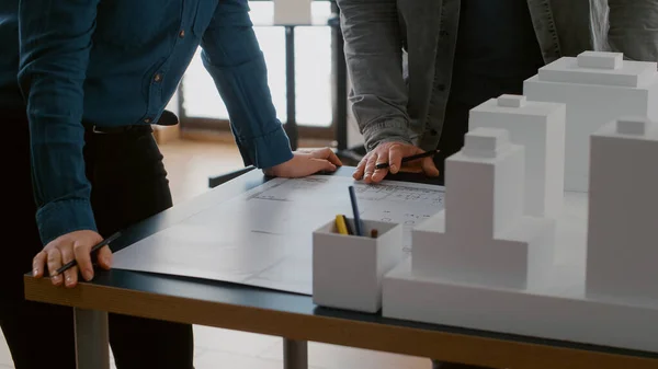 Primer plano de los colegas que trabajan en el diseño urbano con planos y modelo de construcción — Foto de Stock