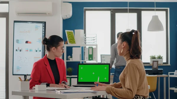 Çalışma arkadaşları masada oturuyor ve dizüstü bilgisayarlarında yeşil ekran kullanıyorlar — Stok fotoğraf