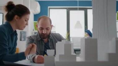 Kadın ve erkek, kağıt üzerinde plan yapmak için model oluşturmaya çalışıyor.