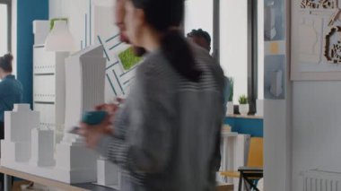 Mimarlık ofisindeki yapı modelini analiz etmek için elinde dizüstü bilgisayar tutan kadın mimar..