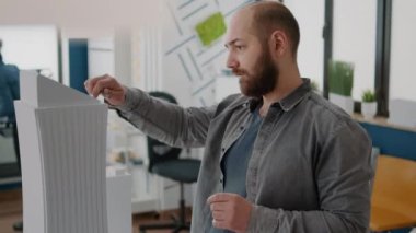 Masadaki kentsel projeyi tasarlamak için inşaat modeli ve maketine bakan bir adam mimarı kapat
