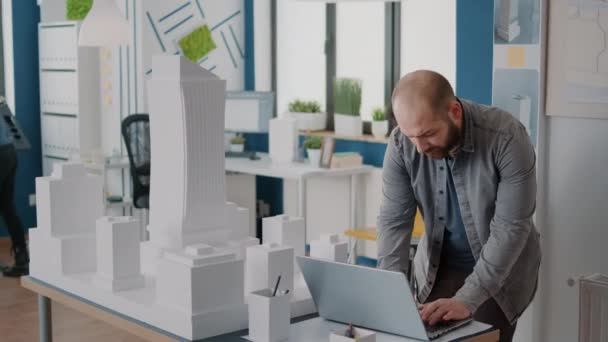 Homem segurando laptop para trabalhar no projeto do modelo de construção e plano de plantas — Vídeo de Stock