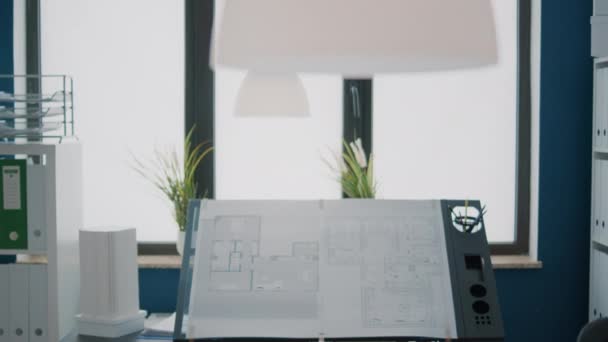 Крупним планом плани креслень на дизайнерському столі в порожньому архітектурному просторі — стокове відео
