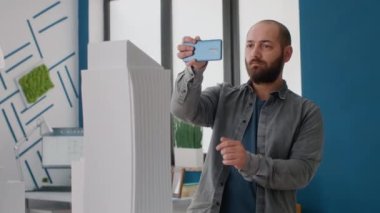 Mimarlık projesinde çalışan adamın cep telefonuyla tasarım modelini kapat