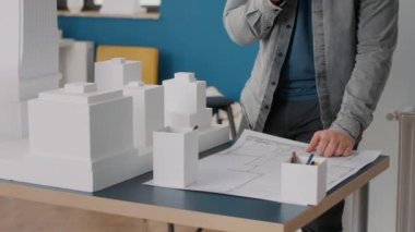 Mimarın model ve maquette üzerinde çalışmak için planlar hakkında notlar almasına yakın plan