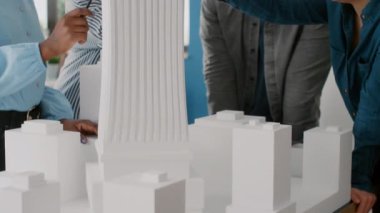 Şehir inşaatını planlamak için masadaki bina modelini analiz eden insanları kapatın.