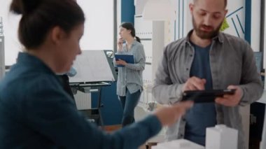 Tablet üzerinde inşaat planı yapmak için maquette ve bina modelini analiz eden çalışma arkadaşları.