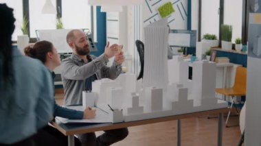 Çalışma arkadaşları masadaki modelden sonra inşaat düzeni tasarlamak için cep telefonu kullanıyor.