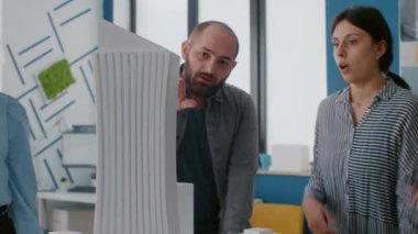 İnşaat yapısını planlamak için bina modelini ve maketini analiz eden iş arkadaşlarını kapat