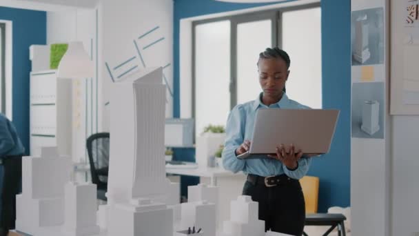 Ingénieur femme travaillant sur ordinateur portable pour planifier la mise en page de contruction avec le modèle de construction et la maquette — Video