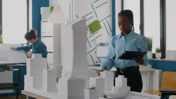 Африканский американский инженер держит планшет для работы над моделью и макетом — стоковое видео