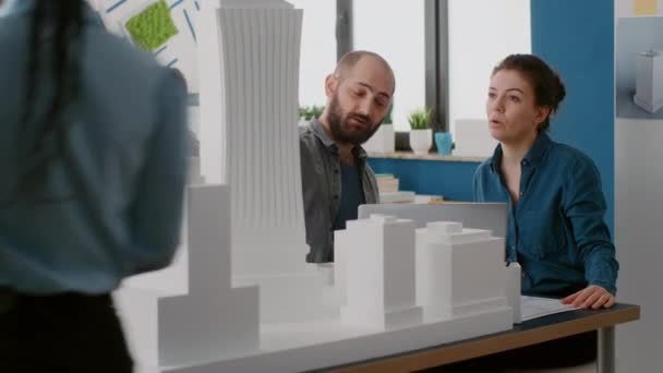Tým architektů navrhujících model budovy na notebooku v architektonické kanceláři — Stock video