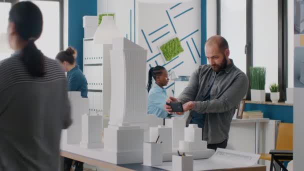 Inżynier człowiek za pomocą smartfona do pracy nad modelem budynku i układu w biurze architektonicznym — Wideo stockowe