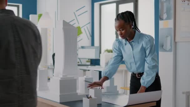 African american architect analyzing blueprints plan and building model at work — Stock Video