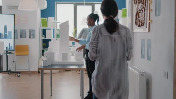 Equipe de diversos arquitetos trabalhando juntos no projeto de modelos de construção com plantas — Vídeo de Stock