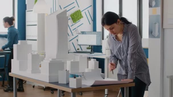 Žena architekt analyzuje plány na stůl navrhnout model budovy a maquette — Stock video