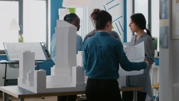 Grupo de pessoas diversas que trabalham no projeto do modelo de edifício com laptop e plantas — Vídeo de Stock