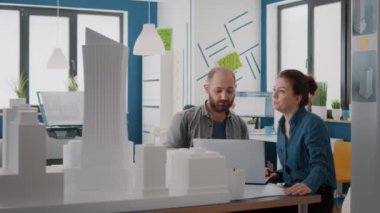 Bina modelini ve tasarım planlarını analiz etmek için laptopta çalışan meslektaşlar