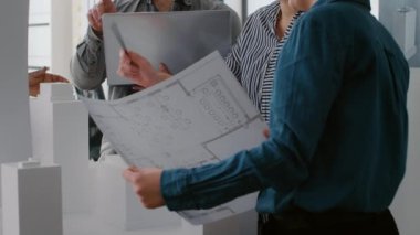 Bilgisayar ve planlarla model tasarımı üzerinde çalışan çalışma arkadaşlarını kapat