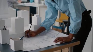 Mimarlık projesinde çalışmak için planlara bakan bir kadın.