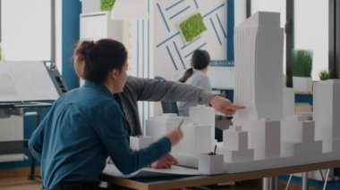 Modeli ve planlarıyla inşaat düzenini tasarlamak için takım çalışması yapan meslektaşlar