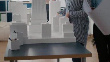 Şehir inşaatını masa üzerinde tasarlamak için planlar kullanan çalışma arkadaşlarını kapat