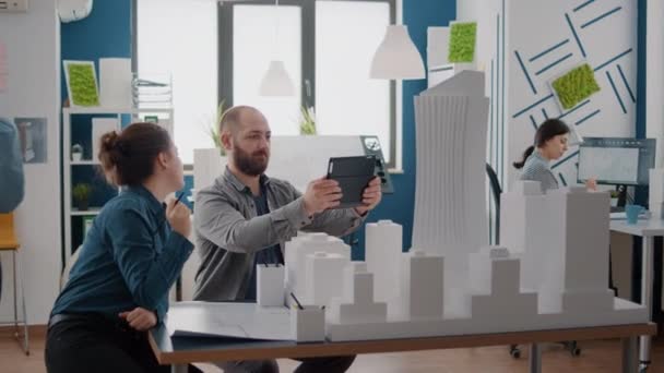 Hombre y mujer analizando modelo de construcción y maqueta con tableta digital para el desarrollo — Vídeos de Stock