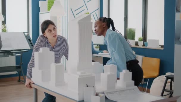 Tým multietnických žen analyzujících maketu na stole, aby navrhli model budovy — Stock video