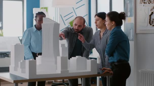 Gruppe verschiedener Kollegen zeigt auf Baumodell, um an einem architektonischen städtischen Projekt zu arbeiten — Stockvideo