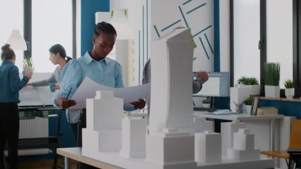 Az afro-amerikai építész portréja, aki tervrajzokat néz az épületmodellel kapcsolatban. — Stock videók