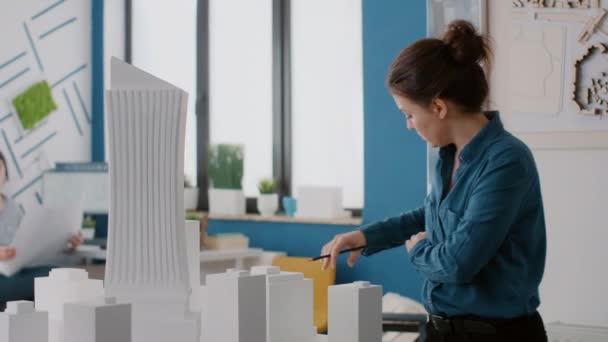 Gros plan de collègues utilisant des plans, un ordinateur portable et une tablette pour concevoir le modèle de bâtiment pour le projet — Video
