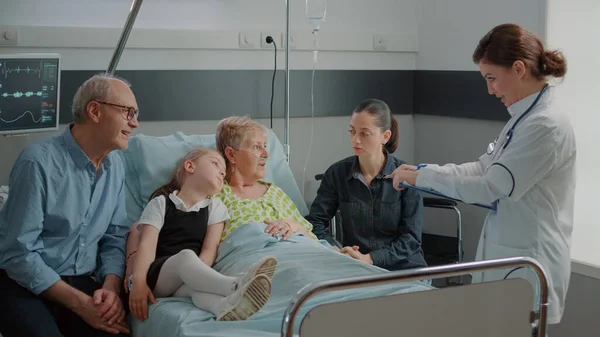 Zieke oma en familie praten met arts over gezondheidszorg — Stockfoto