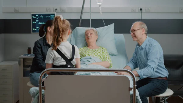 Gepensioneerde patiënt in gesprek met nichtje op familiebezoek in ziekenhuisafdeling — Stockfoto