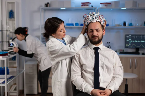 Médecin spécialiste femme mettant eeg casque sur l'homme patient suivi de l'évolution du cerveau — Photo