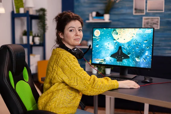 Portrait de femme gamer assis au bureau jeu de tir de l'espace jeux vidéo — Photo