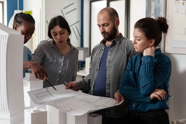 Team di architetti che analizzano i progetti di costruzione in piedi davanti al tavolo — Foto Stock
