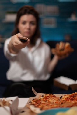 Haber izlerken sesi değiştirmek için televizyonun uzaktan kumandasını tutan kadına odaklan