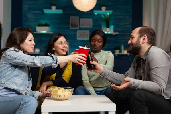 Wekeend partisi sırasında gülümseyen çok ırklı arkadaşlar plastik bardakla bira tokuşturuyorlar.