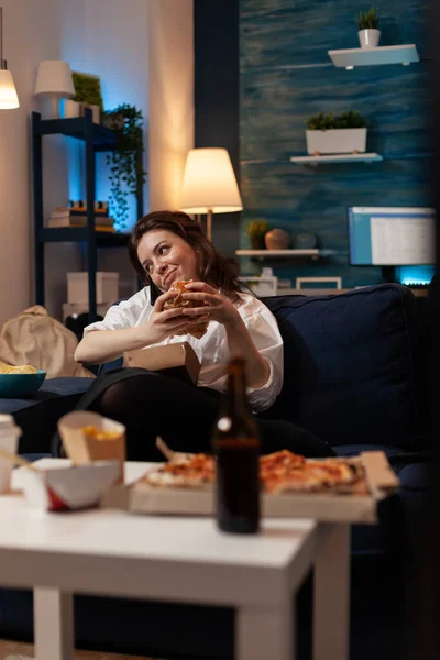 전화 통화를 즐기고 소파에서 편안하게 식사를 하는 여자 — 스톡 사진