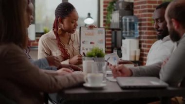 Afro-Amerikalı kadın pano kağıtlarında çizelgeleri açıklıyor.