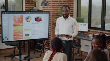 Afro-Amerikalı adam haritalarla finansal sunum yapıyor.