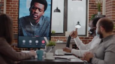 İş adamları online video konferansında adamla konuşuyor.